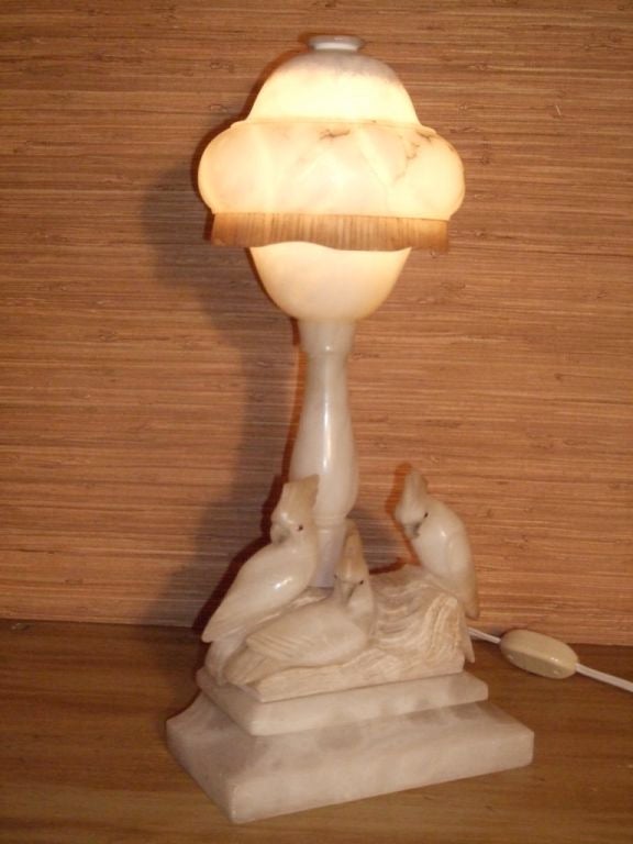 Carved alabaster lamp with bell shaped top, column support and three carved parrots surmounted on a rectangular base.