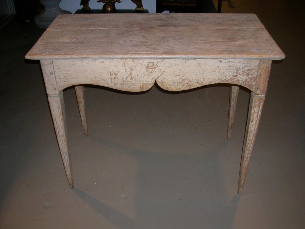 Rectangular wooden side table with decoratively carved apron and original paint.