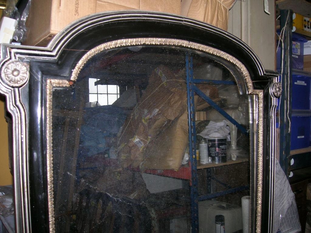 A large scale ebonizied and silver gilt mirror with carved corner rossettes and arched top. Old aged glass with veining.
