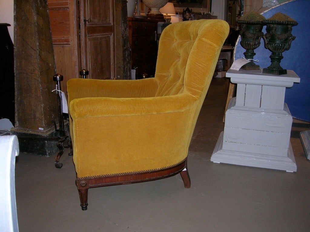 A rosewood tufted club chair with decorative rosettes, brass banding and reeded turned legs.