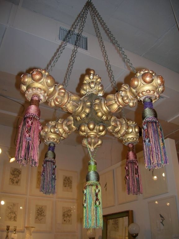 An unusual carved four-arm giltwood chandelier with tassels and retaining its original surface.