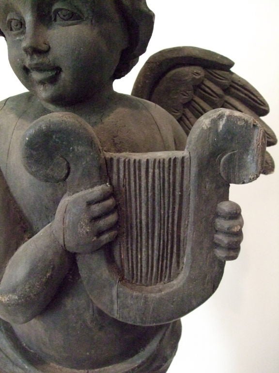 A beautifully carved wooden statue of a standing angel with lyre.