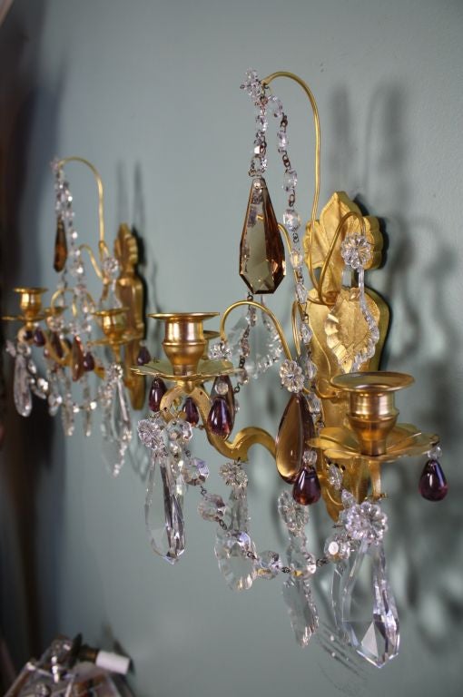 Pair of nice French gilt-bronze three-light sconces in the Louis XV style, with clear crystals, as well as some amethyst and smoke-colored crystals. Pricing includes re-wiring.