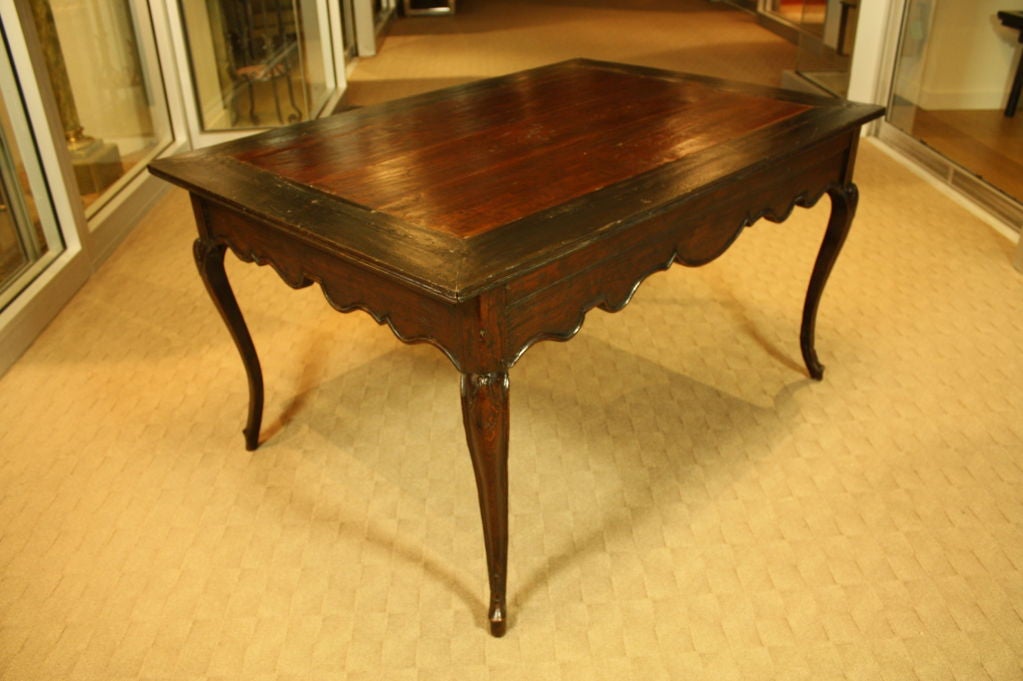 Mesa provincial francesa de época Luis XV con faldón festoneado, patas cabriolé y formas de hojas en las rodillas. El borde se ha teñido de negro.