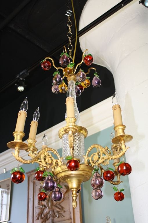 Gilt bronze chandelier with cut crystal central column and colored bohemian glass drops in the shapes of apples and pears. The chandelier dates from the Charles X period (circa 1830), but the fruit drops were probably added later. The chandelier has