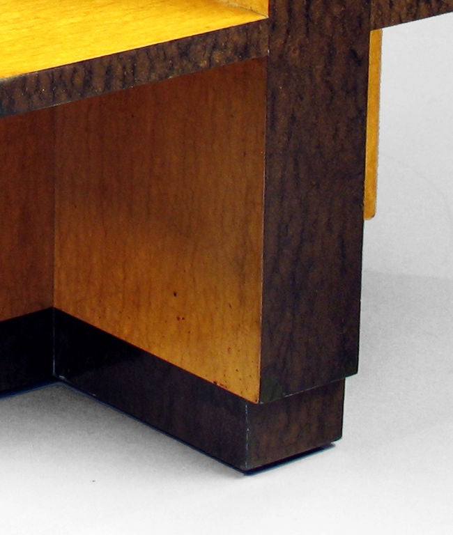 The top with geometric stained burl veneers on cross-shaped support fitted with shelves, raised on conforming foot; the whole with part ebonized burlwood veneers