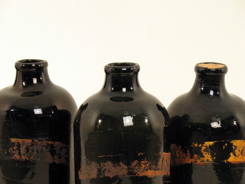 Set of four (4) glass apothecary bottles with hand-rolled rims and gilt labels.