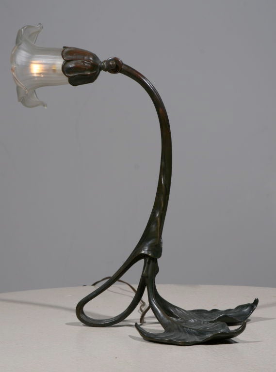 Solid bronze flower table lamp - bronze stem and base, with an adjustable neck, holds a blown frosted glass shade which is sculpted in the form of an open flower, containing a single light. Signed 