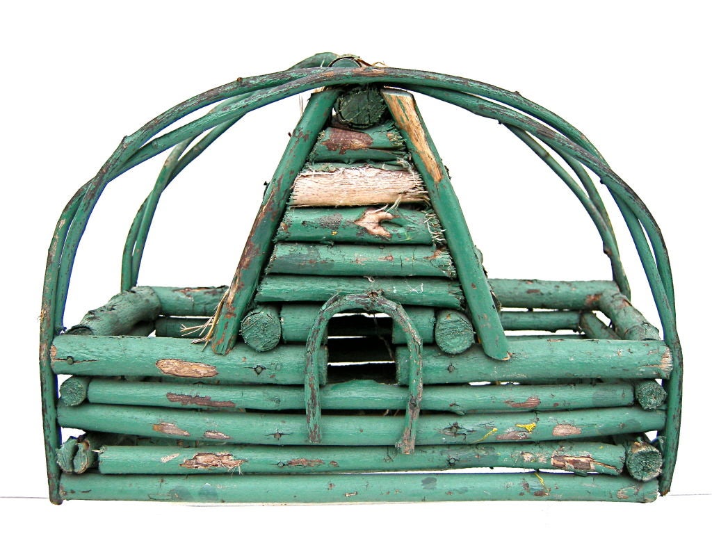 Charming birdhouse constructed in an unusual log cabin style with a more unusual, thatched roof. Vivid, original green paint with curvacious vine handles. For the discerning bird. North Carolina origins.