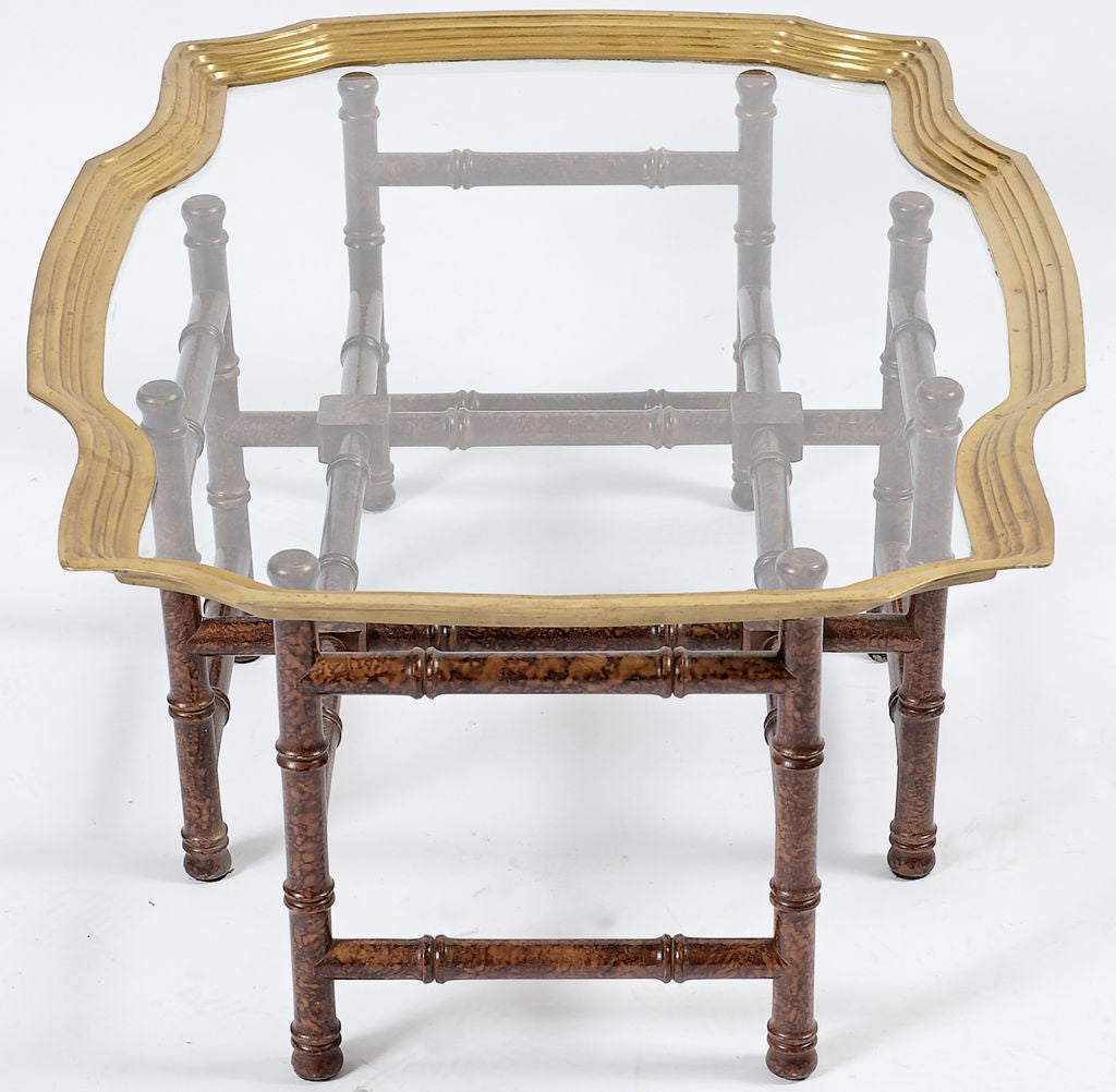 A brass-rimmed glass tray set upon a bamboo-form wooden base that is finished in red and brown faux tortoise shell.