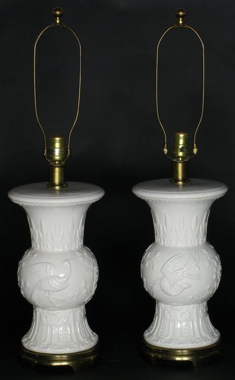 Delightful vintage pair of white porcelain table lamps with raised relief design depicting flora and fauna.  Antique bronze base.  Sold sans shades.