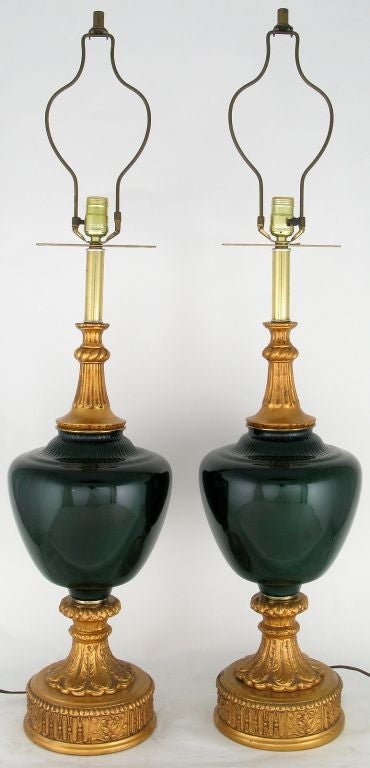Elegant and unusual, these green cased glass and gilt gesso table lamps are quite large and exceptional. Beneath the harp is a pierced bar that allows the hanging of decorative tassels, in the manner of the period. Sold sans shades.