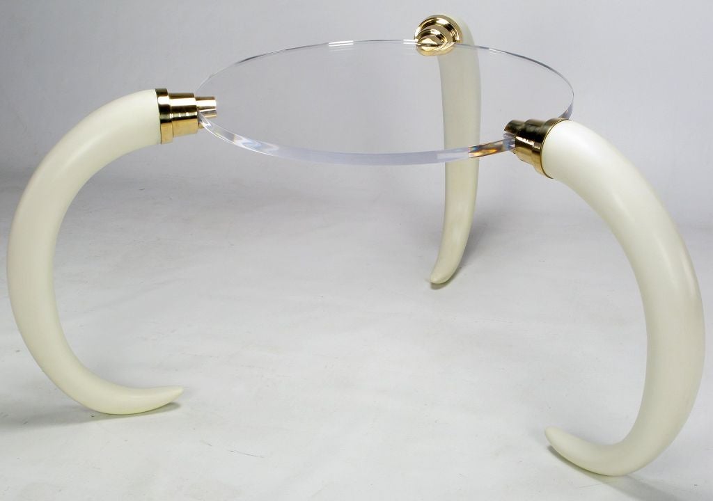 A one-of-a-kind center table consisting of three faux elephant tusks with heavy brass hardware and a 1