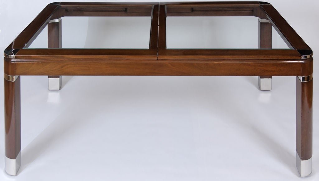Superb dining table made of mahogany and glass, accented by chrome sabots, banding, and corners.  With two leaves.