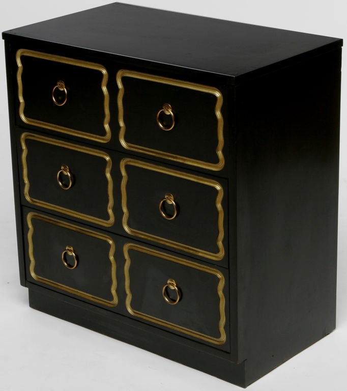 Three drawer chest, or commode, in the manner of Dorothy Draper. Ebonized finish with gold painted inlay. Brass drop ring pulls.