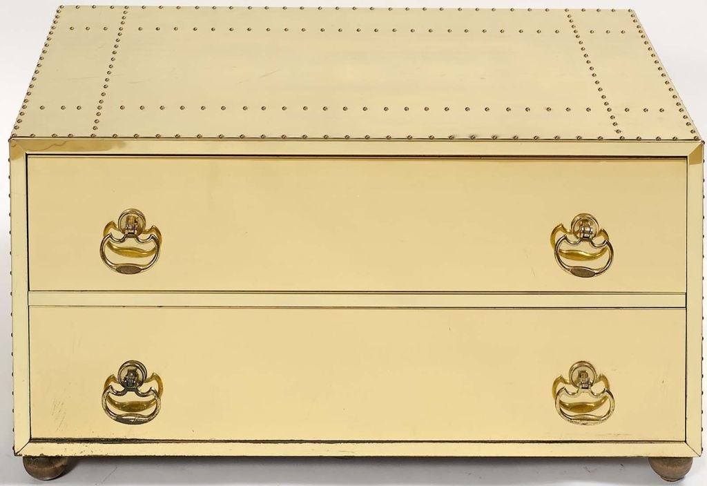Designed to be used as a coffee table, this low brass commode could also be used as a bench.  Completely covered in brass sheet, with patterned nail head trip and stylish cast brass drop pulls, it is set upon four turned wooden legs.