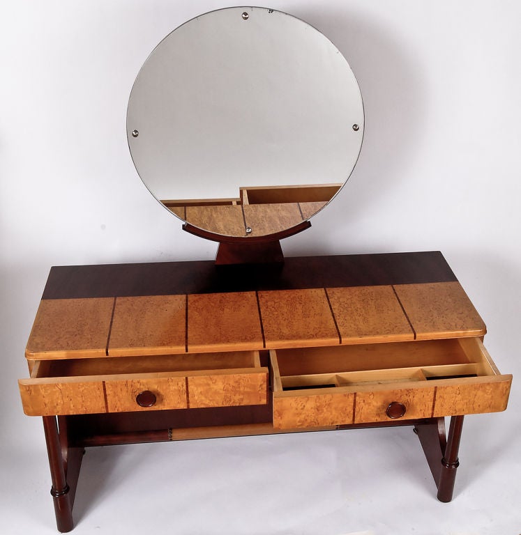 Striking vanity constructed of dark mahogany and lighter burl, by the fine Danish furniture maker, Robert Rasmussen.  Darker strips inlaid in the burl, with leather wrapped footrest.  Round mirror mounted on curule form base.