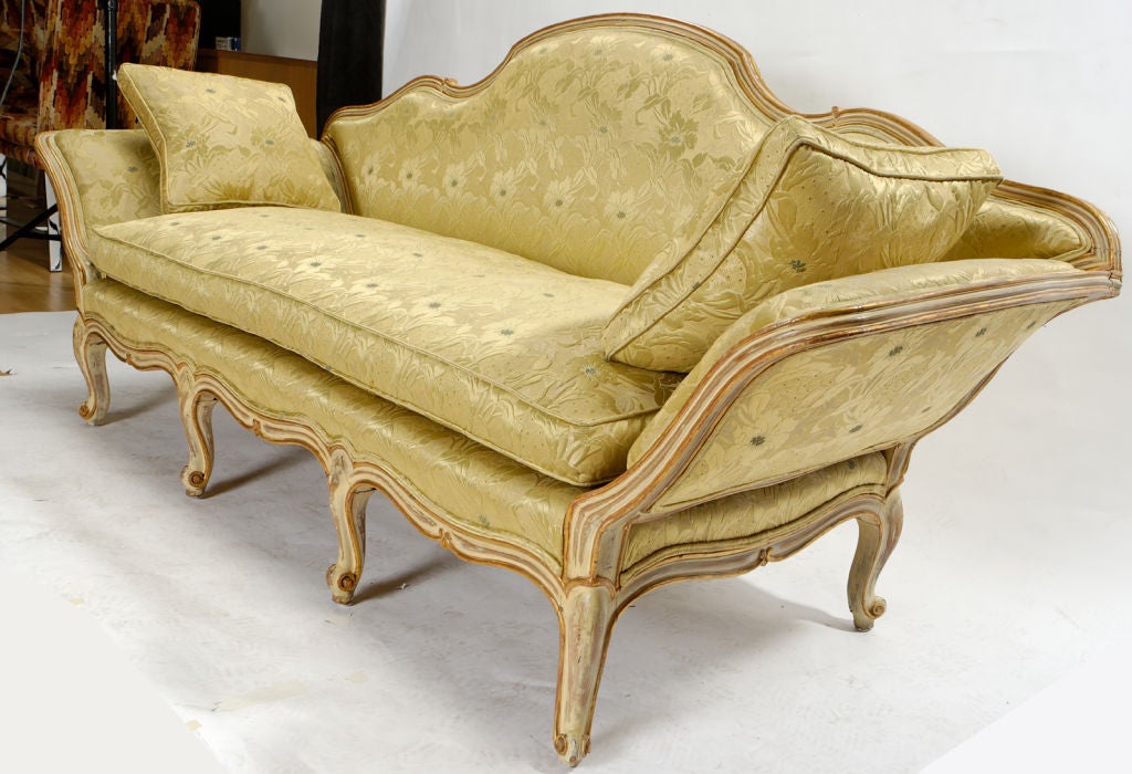 With its fluid lines painted and gilded, the frame of this lovely sofa has a wonderful patina.  Upholstered in a celadon floral damask, with down cushions.