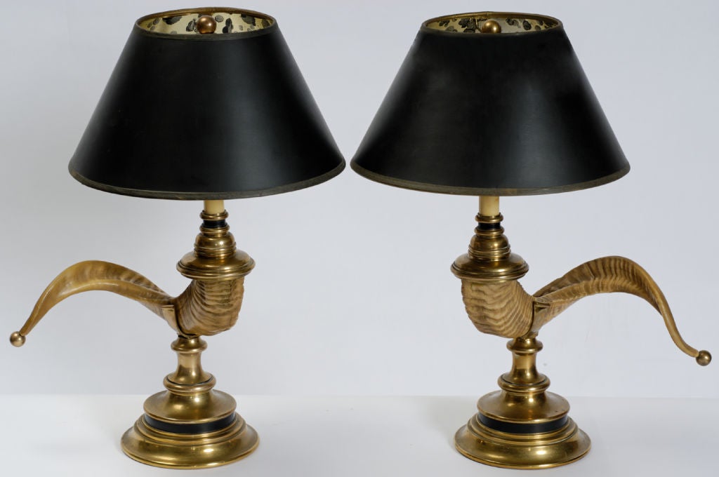 Bronze bases support cast faux ram's horns with ball finial ends, which are surmounted by bronze hardware and candelabra sockets.