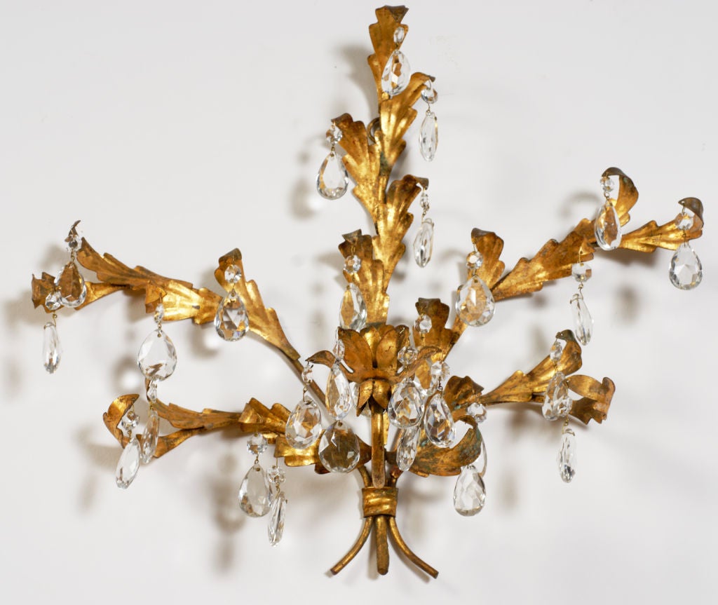 Gilded metal foliage supported by branches. Many crystal drops embellish the fixtures, which have a place for a single candle each.