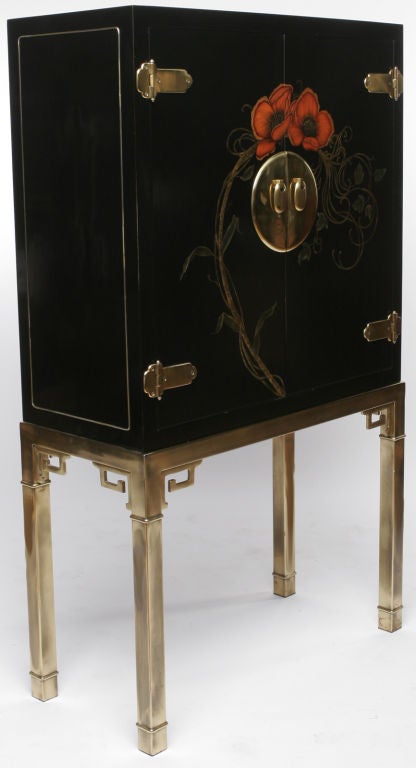 Bronze base with raised detail and Greek key ornamentation, surmounted by a black lacquered bar cabinet, complete with Asian-inspired decorative bronze hardware. A pair of red hand painted poppies adorn the door fronts, while the interior is fitted