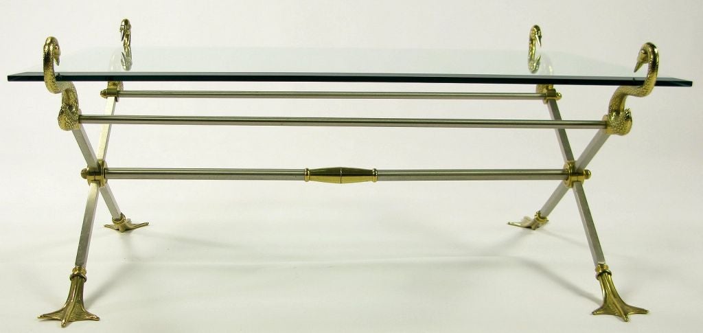 In the manner of Maison Jansen, this lovely table is constructed of nickeled steel saltire ends, joined to each other by three steel rod stretchers.  At the intersection of the cross pieces, a cast brass hub secures the main stretcher to the