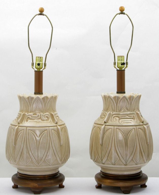 Geschnitzte Holzsockel im chinesischen Design tragen große Keramikkörper, die mit einer Craquelé-Glasur glasiert sind, die die asiatischen Designdetails hervorhebt.  Lackierte Mittelsäulen und originale Endstücke.  Verkauft ohne Schirme.