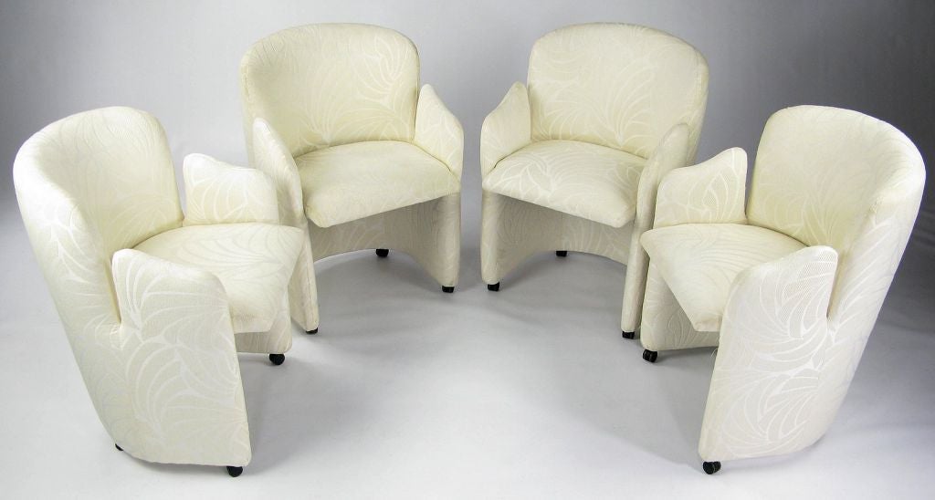 An unusual design, these six dining chairs are created from bent wood frames, with cutout arm designs.  Upholstered in a white tone-on-tone silk blend fabric, with a tropical foliage design.  <br />
<br />
Rolling on small casters for easy