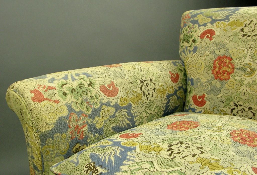 This classic form sofa is supported by carved mahogany cabriole legs.  Vintage upholstery in a Chinese design, with colors of gray, yellow, green, blue, and red.  Down filled cushions.