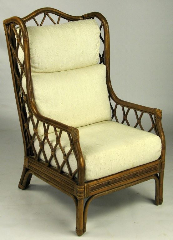A traditional Chippendale form is interpreted in the non-traditional material of rattan.  Treillage inserts in the back and side panels maintain the lighter feel, with the subtle light upholstery accenting the darker frame.