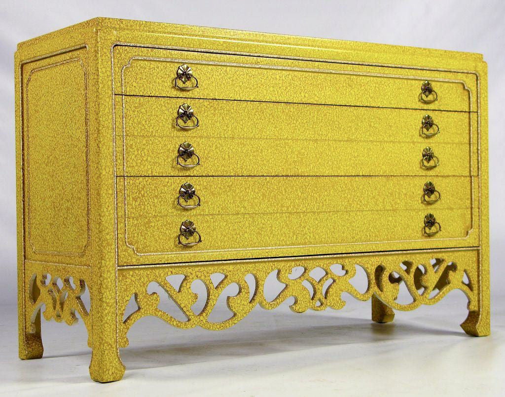 This three drawer chest has a case crafted in a somewhat Asian style, with open Art Nouveau fretwork on the fronts and sides.  Finished in yellow, white and light umber oil drop lacquer.   Antiqued brass drop ring pulls with backing rosettes.  <br