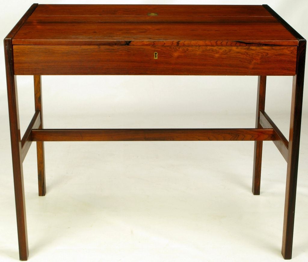 In the manner of Grete Jalk, this Danish writing desk or secretary is clad completely in rosewood veneer over maple. Wonderfully compact, this Danish export features a large center drawer and a slanted writing surface. A flip-top lifts to reveal