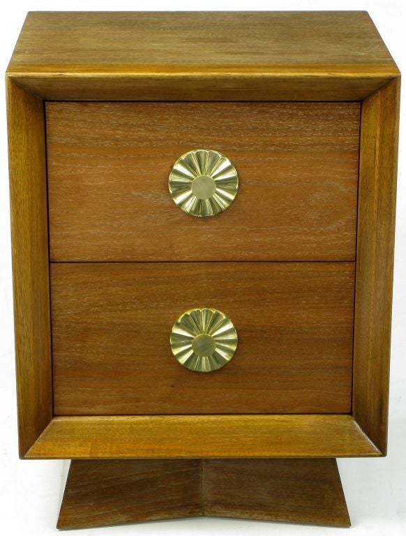 This cerused walnut nightstand has many style points in the manner of Tommi Parzinger. Exaggerated brass sunburst escutcheons with solid brass pulls. Beveled plinth base, as well as the inset drawers, all come together to form a striking, yet clean
