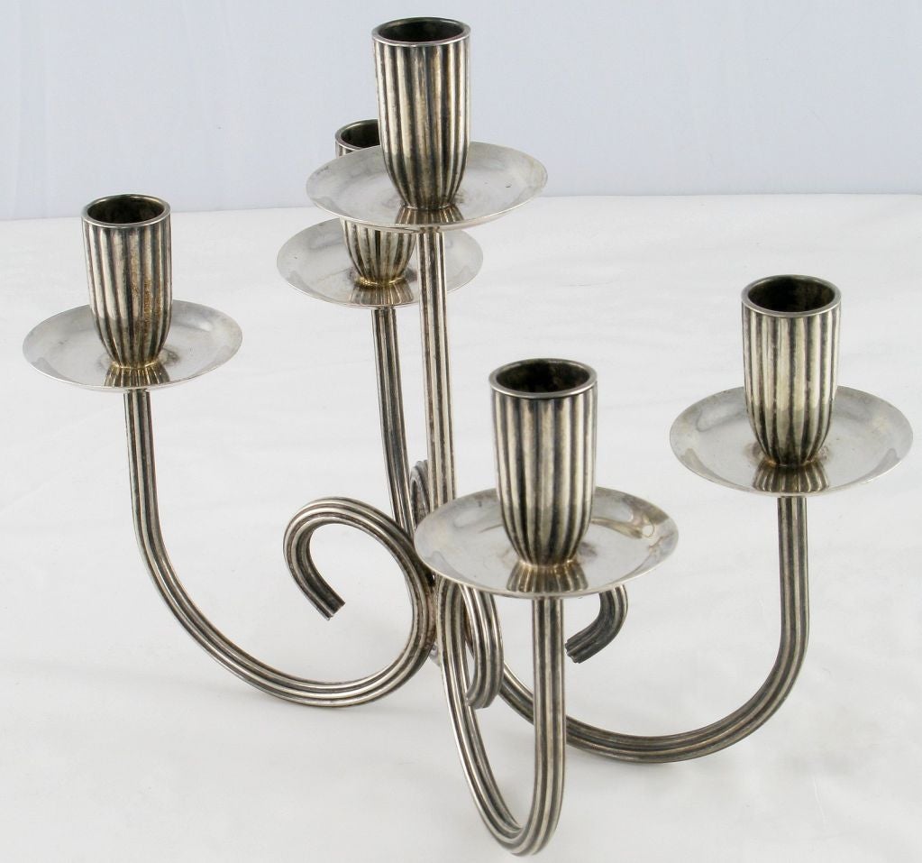 Exquisite scrolled arm candelabra in silver. Four outer arms and one central stem rising up from middle.