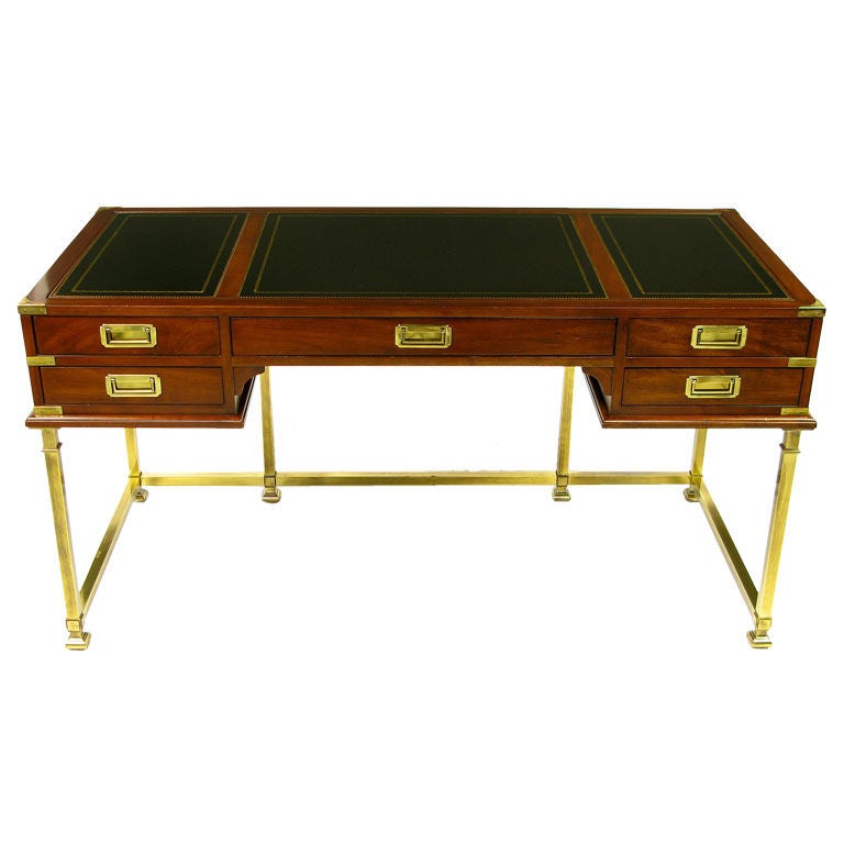 A classic form, accented by the brass base, this campaign desk is of a size to fit in many locations. Brass bound corners, and flush campaign pulls contrast nicely with the mahogany finish, and gilt black leather top. Also a perfect writing table,