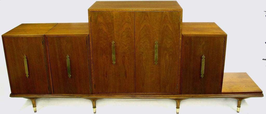 Very rare and unusual piece by Edward Wormley. This modular credenza in walnut can be put together in a host of different configurations. Detailed with large Moorish style solid brass pulls and brass sabots.