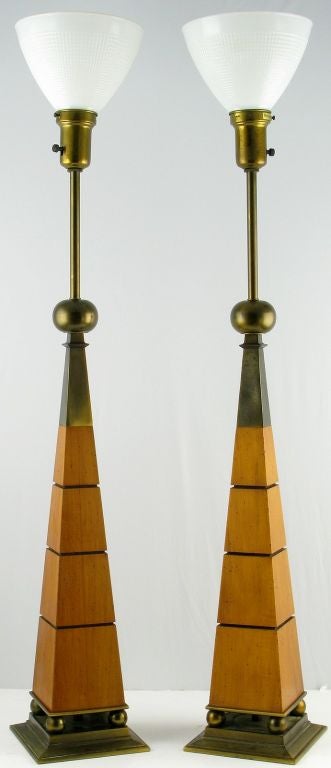 Architecturally inspired pair of table lamps by Stiffel.Four brass spheres atop a plinth base support a walnut obelisk-form body with horizontal incised and ebonized decoration. Surmounting the wood is a brass obelisk topped by a larger brass sphere