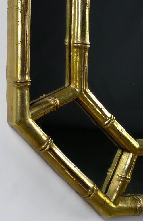 Elegant faux bamboo mirror in patinated gold leaf with segmented mirrored border.