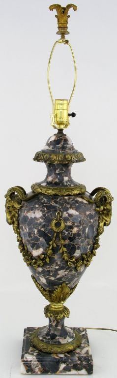 This very fine and heavy black and rouge marble urn, adorned with bronze rams heads and bronze ormolou, has been crafted into an elegant table lamp. Bronze dore plume finial.  Quite substantial, and most likely French. Sold sans shade.