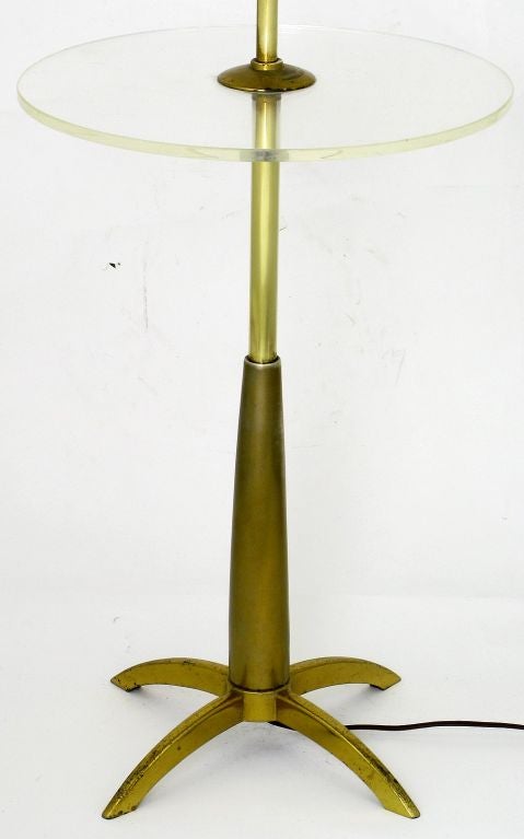 Modern floor lamp in brass with a round clear acrylic table top by Stiffel. Solid brass base with four arched legs and dual lighting elements with classic pull chain switches. Sold sans shade.