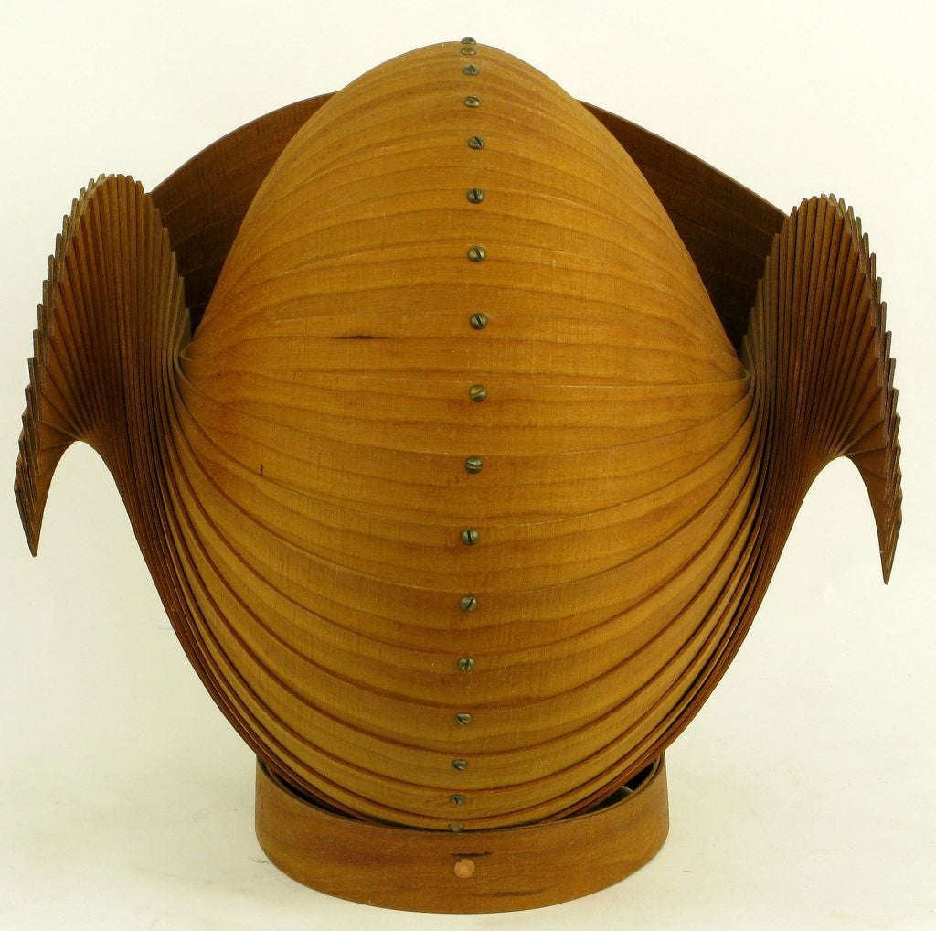 A beautiful creation, this stylized nautilus shell is constructed of a series of bent wood strips connected by brass nail head rods and rests on a circular bent wood plinth.