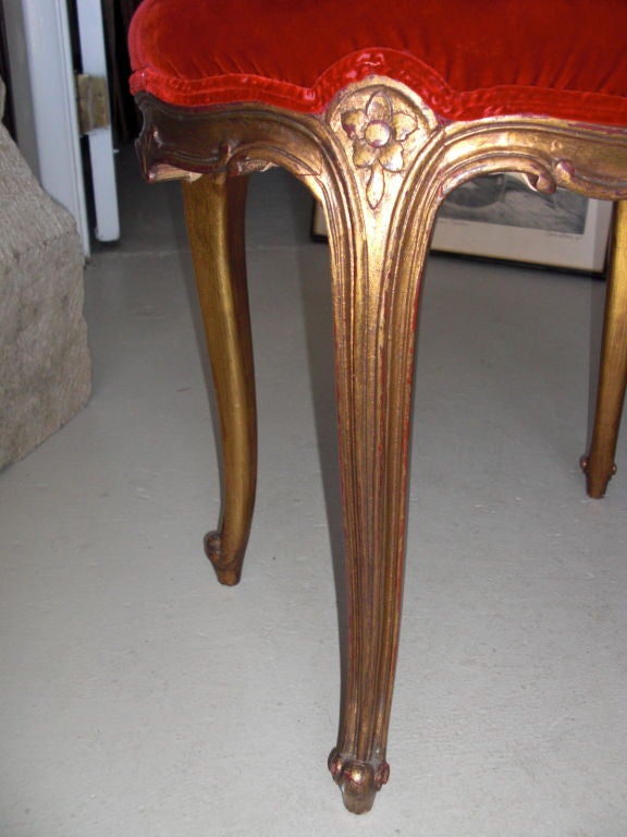 A nice example of a Louis XV style carved and gilt wood little bench with vintage red velvet upholstery.