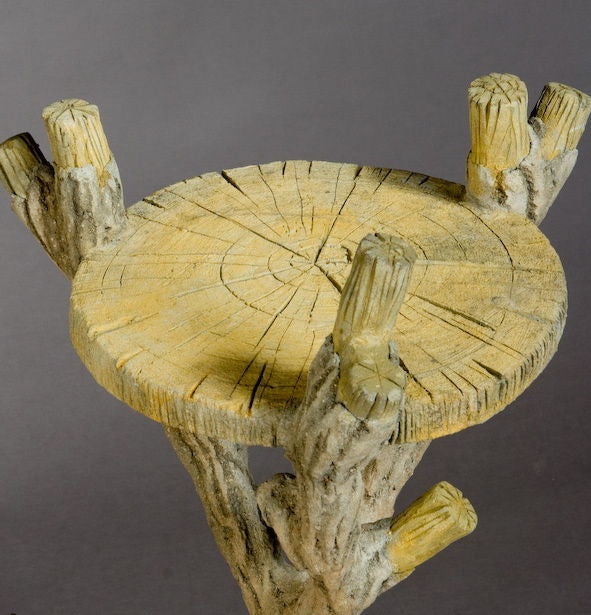 A pair of rustic, French, cement tables with legs simulating tree branches. The table tops are in the form of a cross section of a tree trunk.
