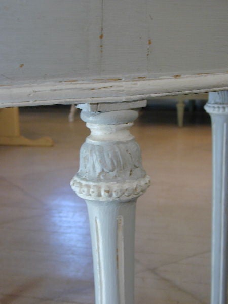 A painted, grey and white, Continental Center Table with four drawers, reeded legs and carved collars.