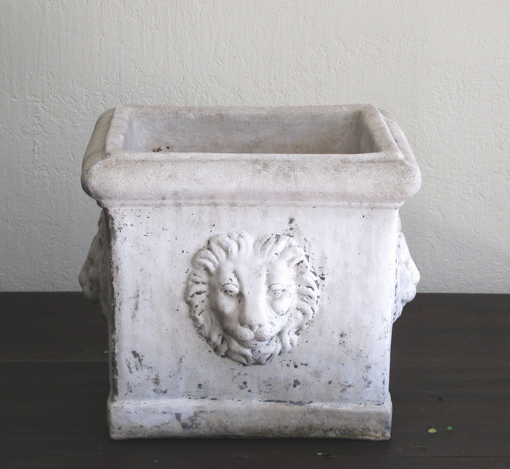 A pair of concrete planter boxes<br />
square form with lion face relief<br />
on all four sides.<br />
Drain hole at base.