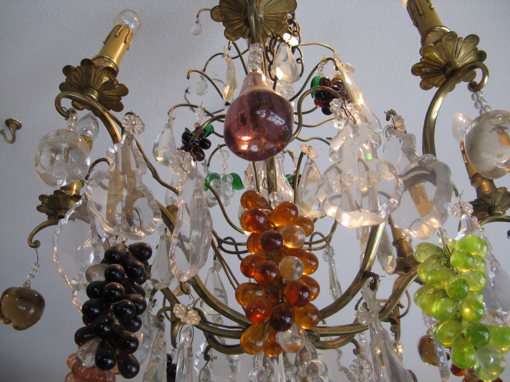 A cornucopia of colored fruit is suspended from a golden bronze frame.  This 1930's chandelier is made up of grapes, pears, and apples in vibrant jewel tone colors that actually glow when the six armed piece is lit.  The light is reflected from the