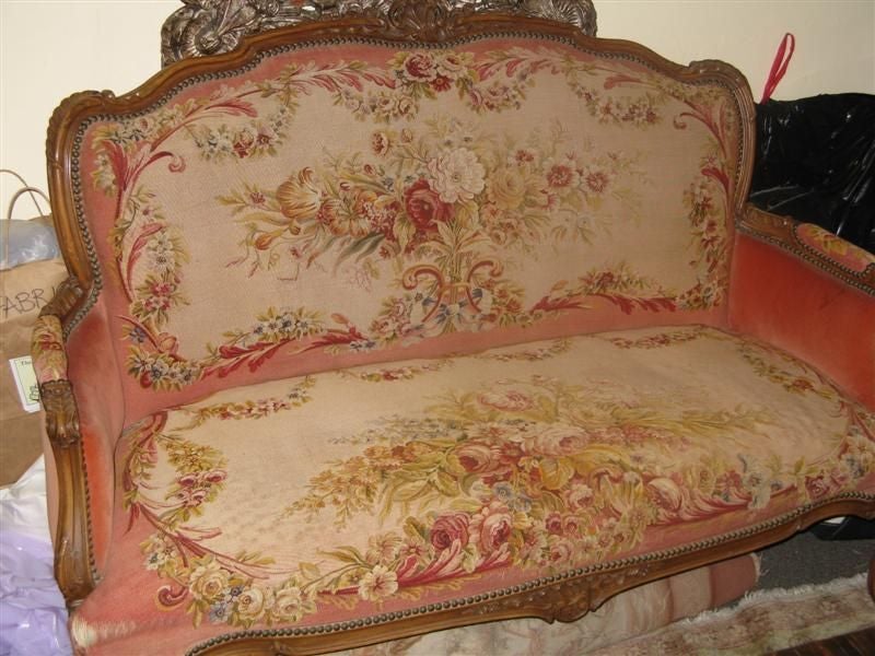 This French carved walnut settee is magnificiently upholstered in a handcrafted floral Aubusson textile.  The creme background is decorated with bouquets and garlands of flowers.  The primary colors are rose, pink, gold, peach, coral, crimson,