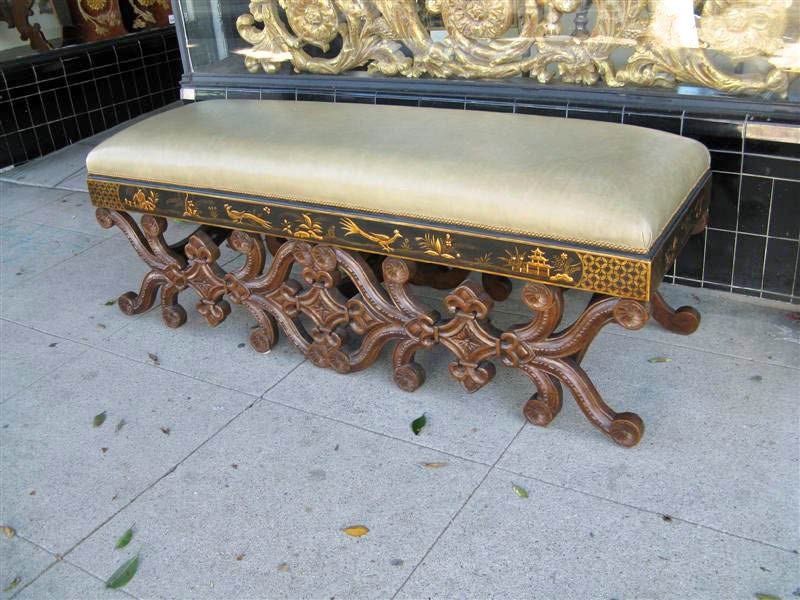Strutting peacocks walk amid pagodas, gardens and cottages in this chinoserie apron of this walnut carved bench. Three stretchers connect the pair of highly carved panels depicting fleur-de-lis and pinwheels.  Elegant moss colored leather is