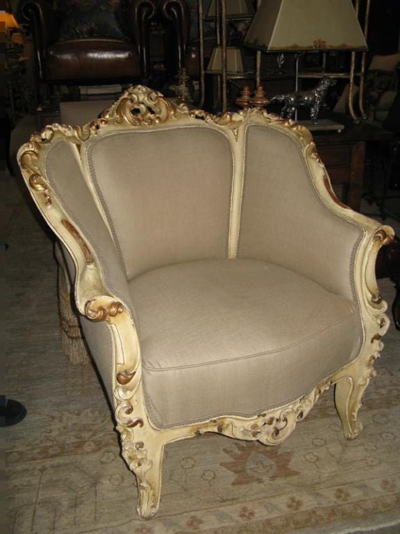 Grand pair of Rococo style antique creme colored painted and parcel gilt Armchairs.  These chairs have been reupholstered in an elegant washed linen fabric that matches any decor and are ready to be installed in your home.  Extra deep, roomy, &