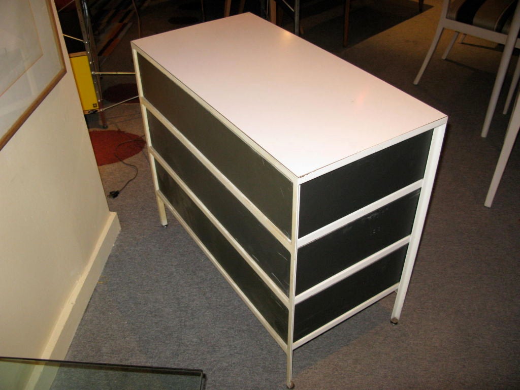 chest of drawers with painted white steel frame drawer fronts of orange painted wood with sides painted olive.  When drawers are pulled out they reveal a negative space
